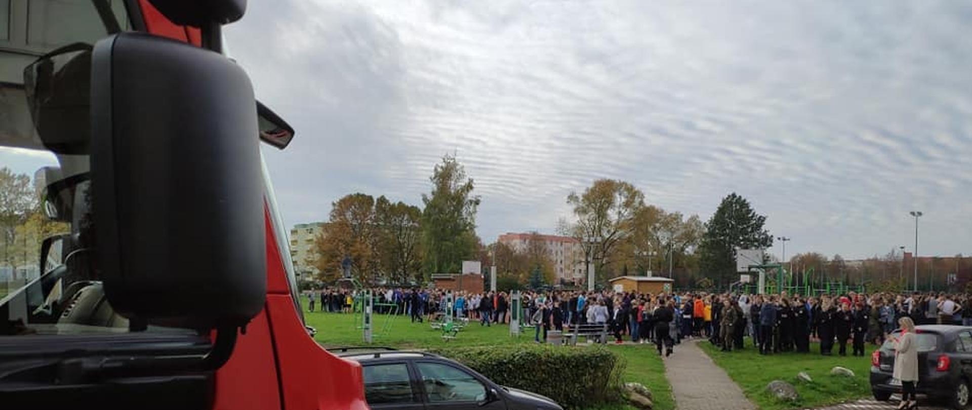 Dzieci na placu przed szkołą, po lewej kabina samochodu gaśniczego