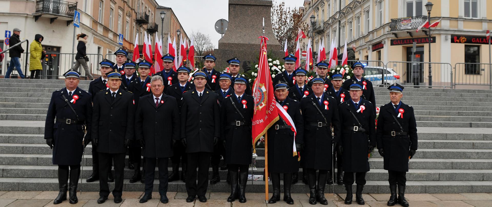 Zdjęcie przedstawia przedstawicieli służb stojących wraz z wojewodą świętokrzyskim pod pomnikiem Józefa Piłsudskiego.