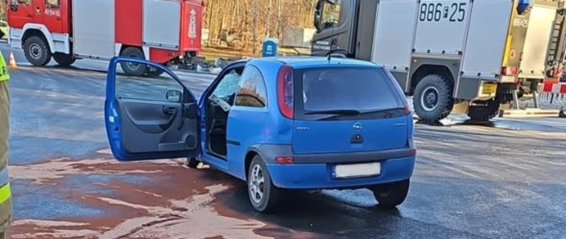 Auto osobowe na jezdni, w tle wóz strażacki i Komendy Poligonu