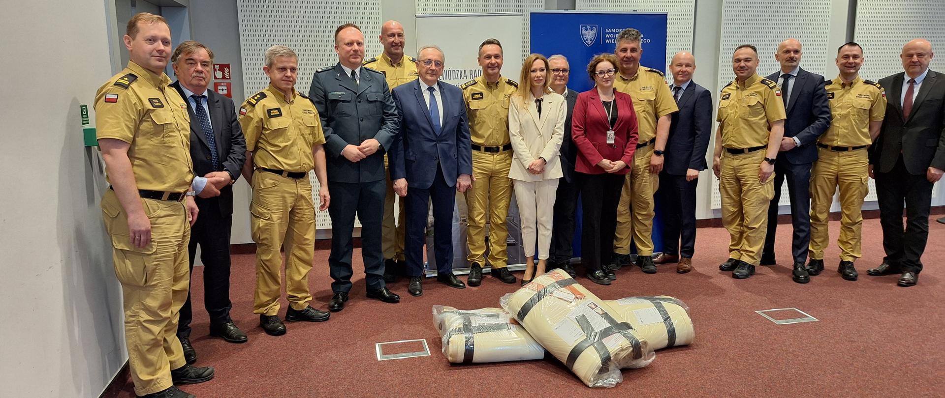 Strażacy oraz marszałek i dyrektorzy word stoją podczas przekazania płacht gaśniczych
