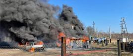 Widać pożar budynku i samochodu osobowego, jest czarny dym