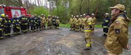 Zdjęcia przedstawia strażaków stojących na zbiórce podczas ćwiczeń z zakresu zaopatrzenia wodnego na obszarach leśnych.