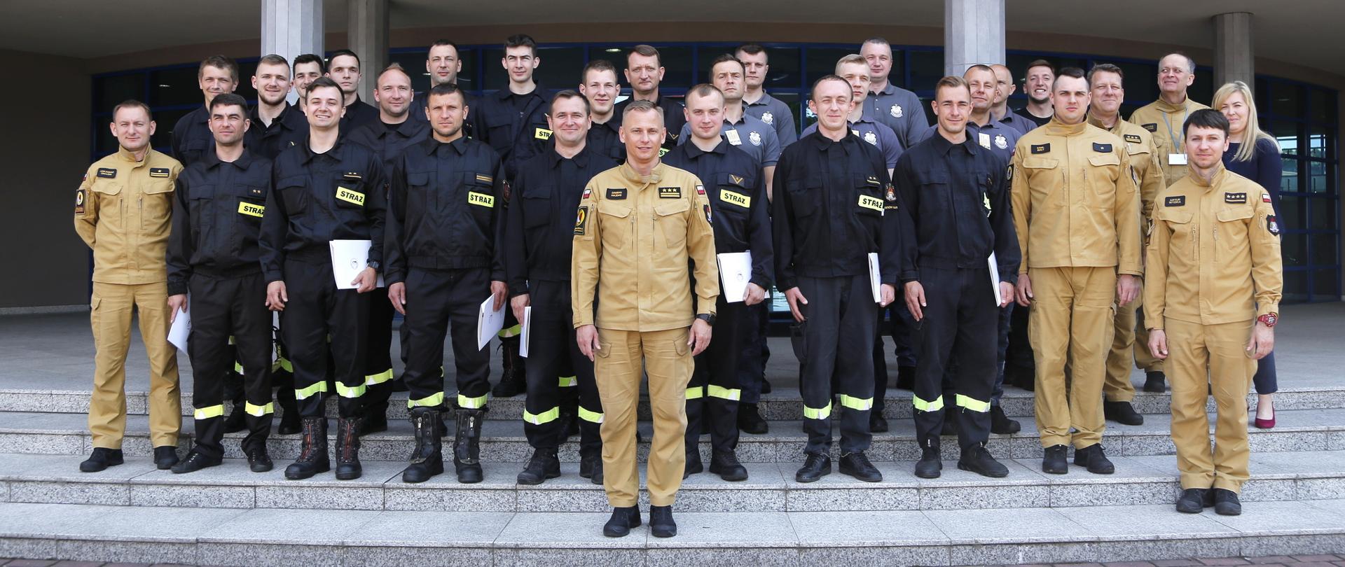 Grupowe zdjęcie uczestników szkolenia (23 funkcjonariuszy) w towarzystwie Zastępcy Komendanta Centralnej Szkoły PSP, kobiety oraz pięciu funkcjonariuszy CS PSP