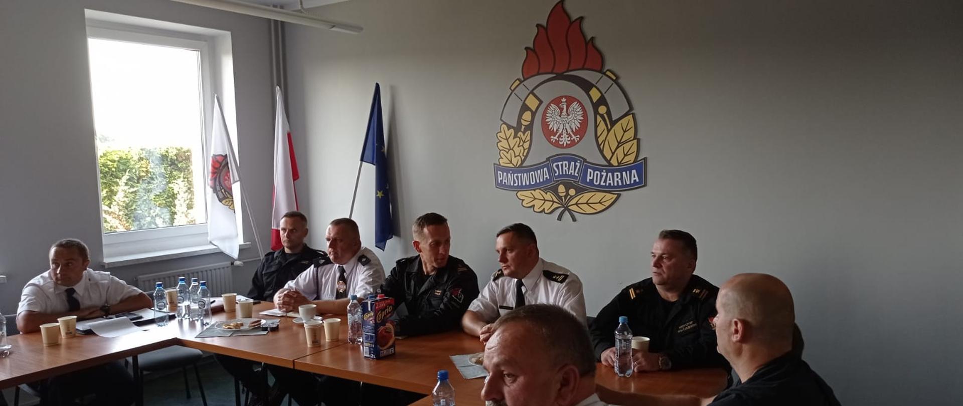 Uczestnicy odprawy - strażacy zasiadający za stołem