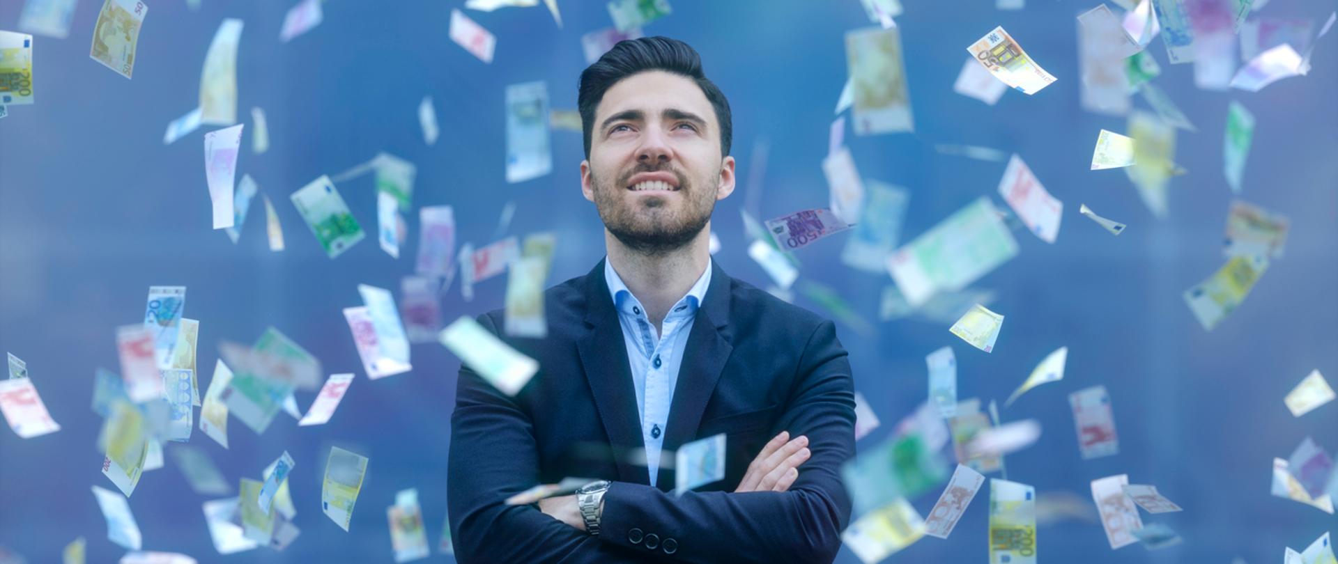 Businessman patrzy na spadające z nieba banknoty. 