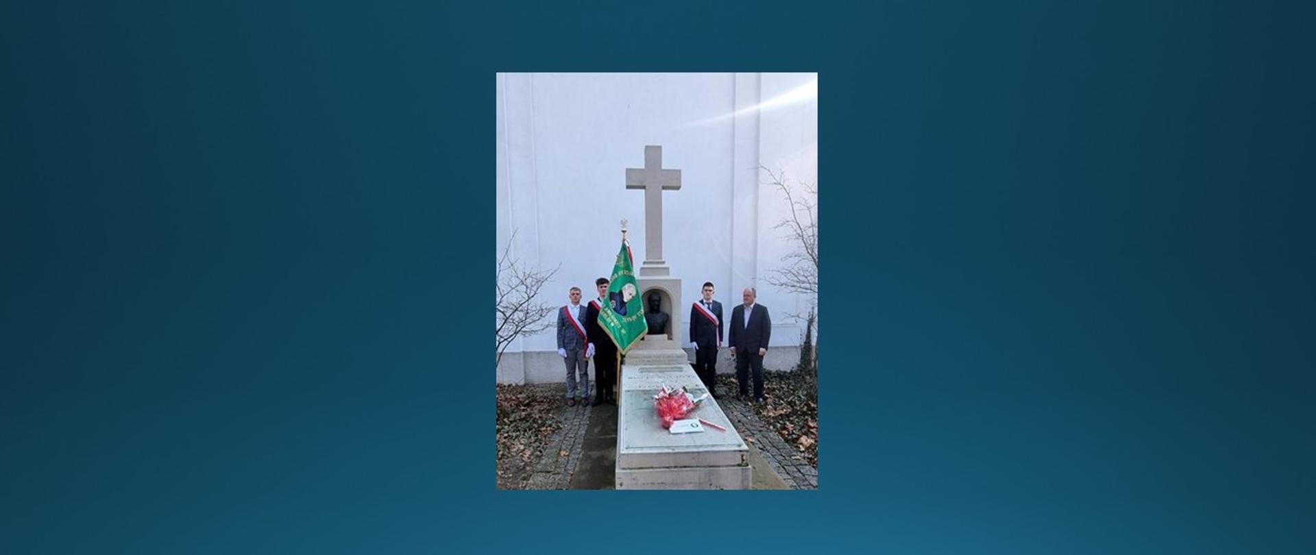 Mężczyzna oraz poczet sztandarowy stoją przy grobie.