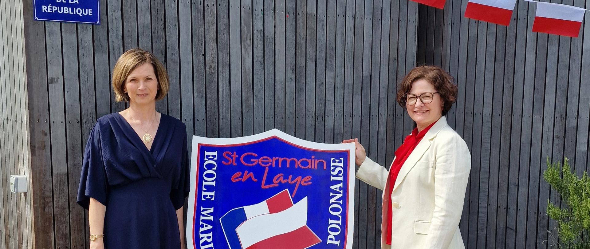 L'écusson de l'école primaire Marie Curie de Saint-Germain-en-Laye. Deux femmes se tiennent de part et d'autre.