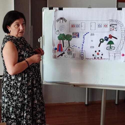 Kobieta przy tablicy z planem nowego placu zabaw