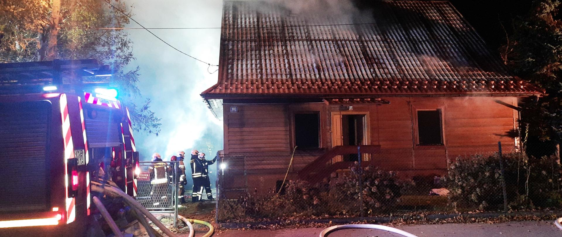 Płonący budynek oraz strażacy prowadzący działania