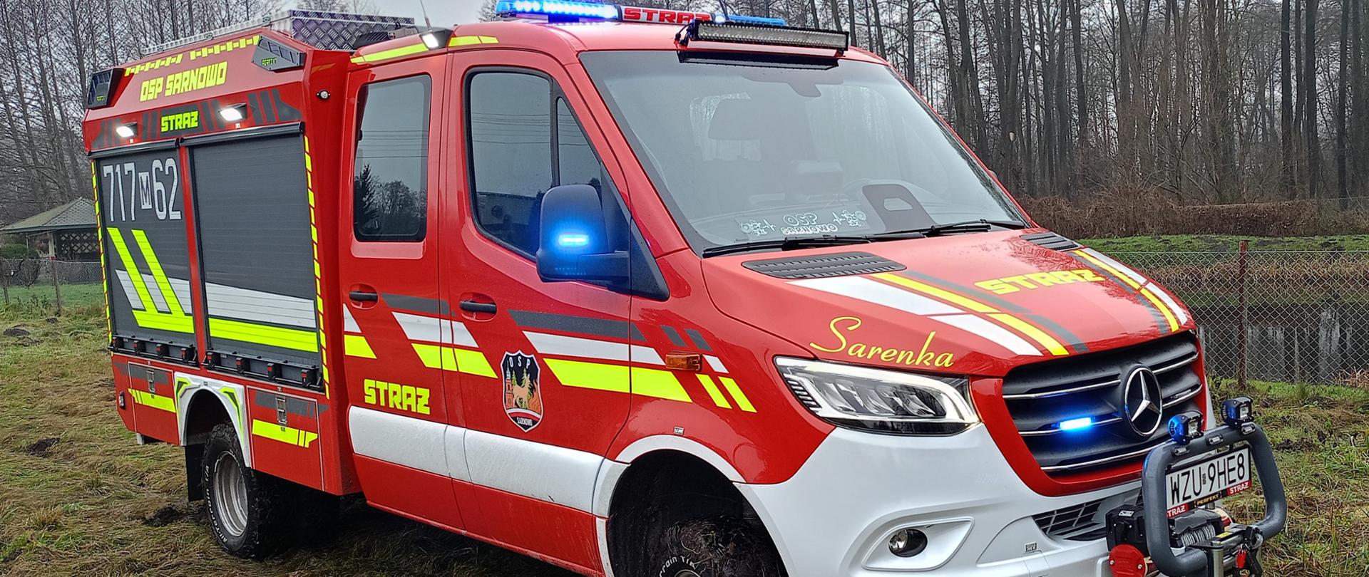 Zdjęcie przedstawia nowoczesny, lekki samochód ratowniczo-gaśniczy marki Mercedes-Benz Sprinter należący do jednostki OSP Sarnowo. Pojazd wyróżnia się intensywną czerwoną barwą z elementami odblaskowymi, pełnym oświetleniem ostrzegawczym oraz specjalistycznym wyposażeniem, takim jak wyciągarka i zabudowa kontenerowa.