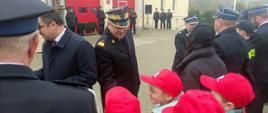 Mężczyzna oraz strażak wręczają promesy przedstawicielom Młodzieżowych Drużyn Pożarniczych.