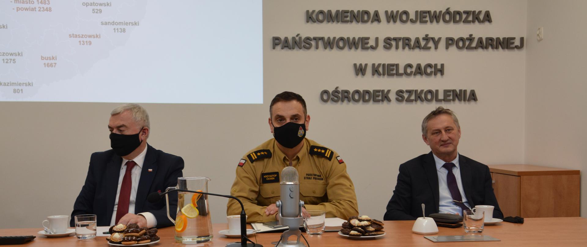 Zdjęcie przedstawia stół prezydialny, za którym siedzą Wojewoda Świętokrzyski Zbigniew Koniusz, Marszałek Województwa Świętokrzyskiego Andrzej Bętkowski, Świętokrzyski Komendant Wojewódzki PSP w Kielcach st. bryg. Krzysztof Ciosek
