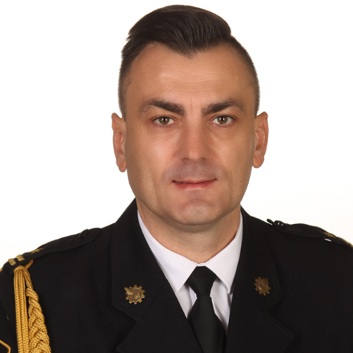 Zdjęcie profilowe Komendanta Powiatowego PSP w Rawie Mazowieckiej mł. bryg. Konrada Krupa na jasnym tle w mundurze galowym.