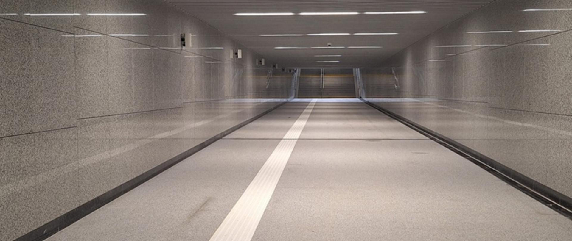 Puste przejście podziemne z prowadnicą dla niewidomych i schodami na końcu.