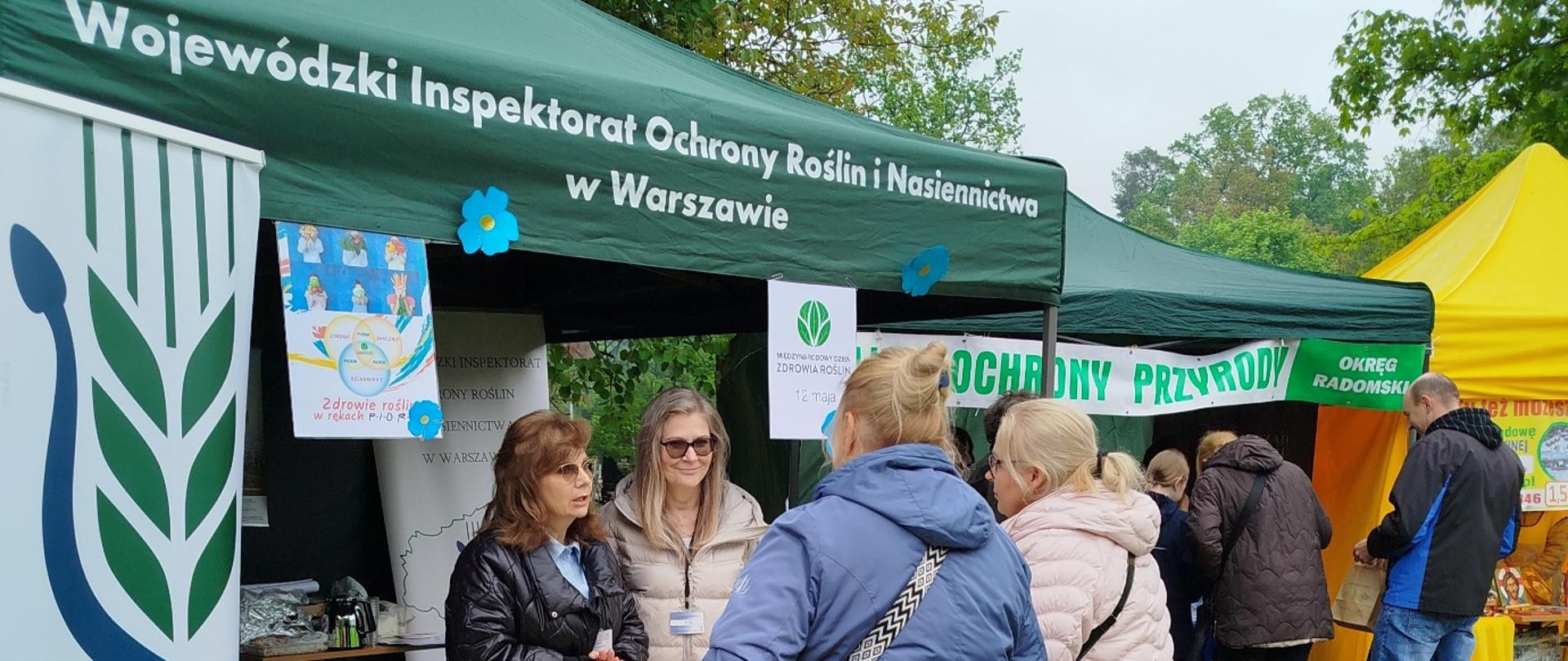 Stoisko Wojewódzkiego Inspektoratu Ochrony Roślin i Nasiennictwa w Warszawie podczas plenerowego wydarzenia edukacyjnego, odwiedzane przez uczestników.