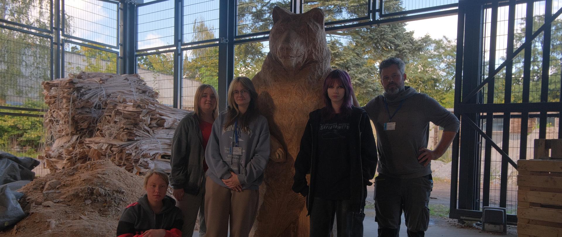 zdjęcie grupowe, uczniowie z nauczycielem pozują przy dużej rzeźbie niedźwiedzia