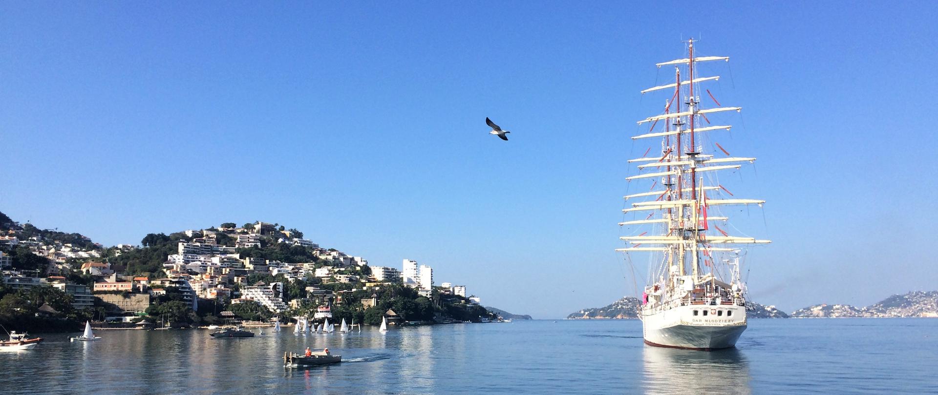 Żaglowiec wpływający do portu. W tle wzgórza i miasto Acapulco