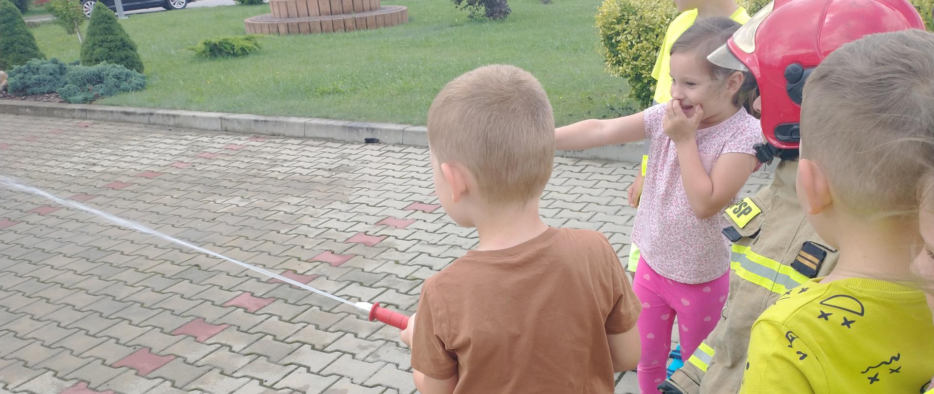 Strażak podaje wodę z prądownicy 