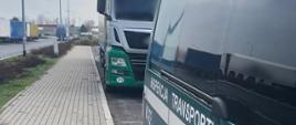 Na pierwszym planie (od prawej): bok oznakowanego furgonu mazowieckiej Inspekcji Transportu Drogowego. Za nim stoi kontrolowany ciągnik siodłowy z podpiętą naczepą. W tle (od lewej): ciężarówki zaparkowane na parkingu MOP Mroków.