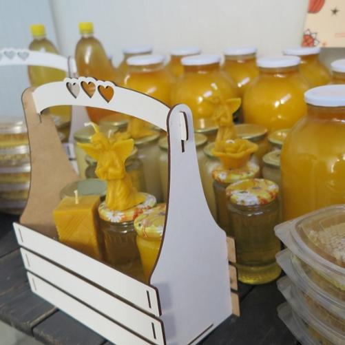 Wyroby pszczelarstwa w słoikach, plastikowych pudełkach i koszyku.