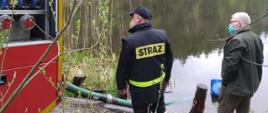 Widok próby zassania wody przez samochód ratowniczo-gaśniczy z punktu czerpania wody w towarzystwie leśniczego.