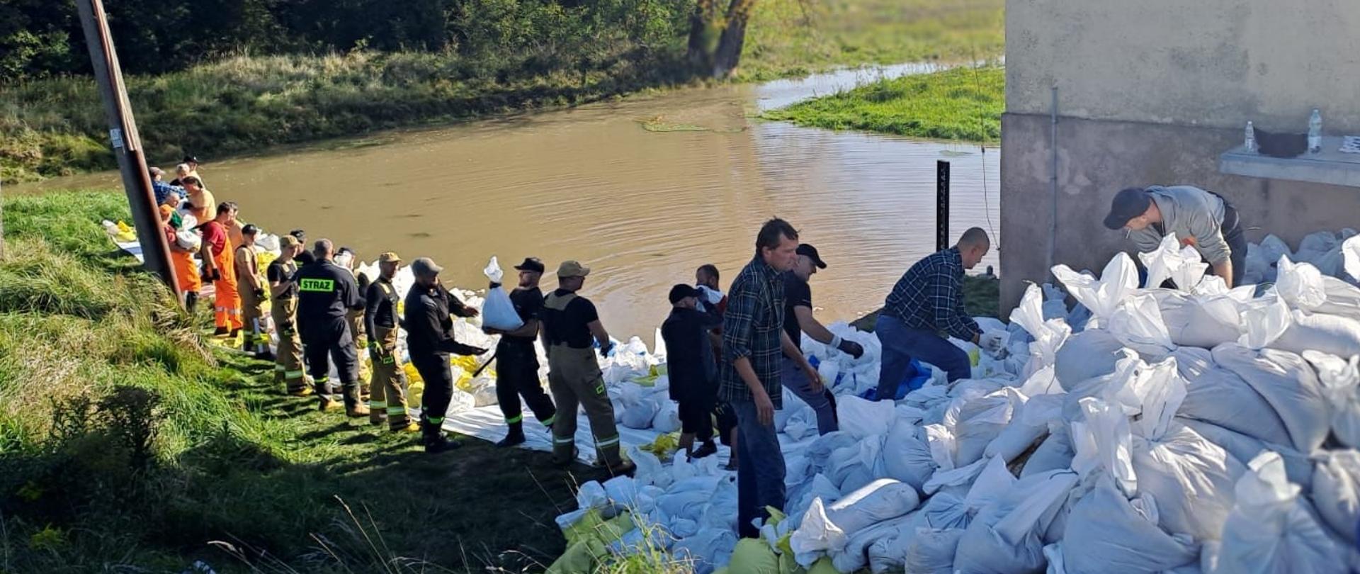 Strażacy układają worki z piaskiem