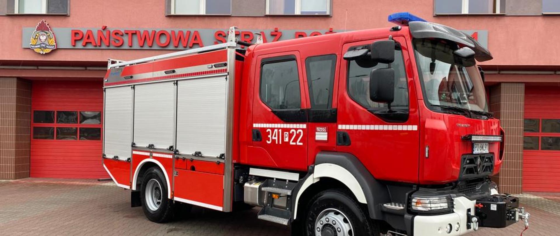 Na zdjęciu widać pojazd ratowniczo-gaśniczy na podwoziu Renault z zabudową firmy Stolarczyk. Pojazd czerwony. Posiada białe oznaczenia. Posiada sygnalizację ostrzegawczą. Żaluzje zamknięte na zabudowie. W tle budynek JRG 1 Kalisz. Pojazd stoi na kostce brukowej. Pora dnia to dzień. Na pojazdem fragment napisu Państwowa Straż Pożarna. W tle bramy garażowe.
