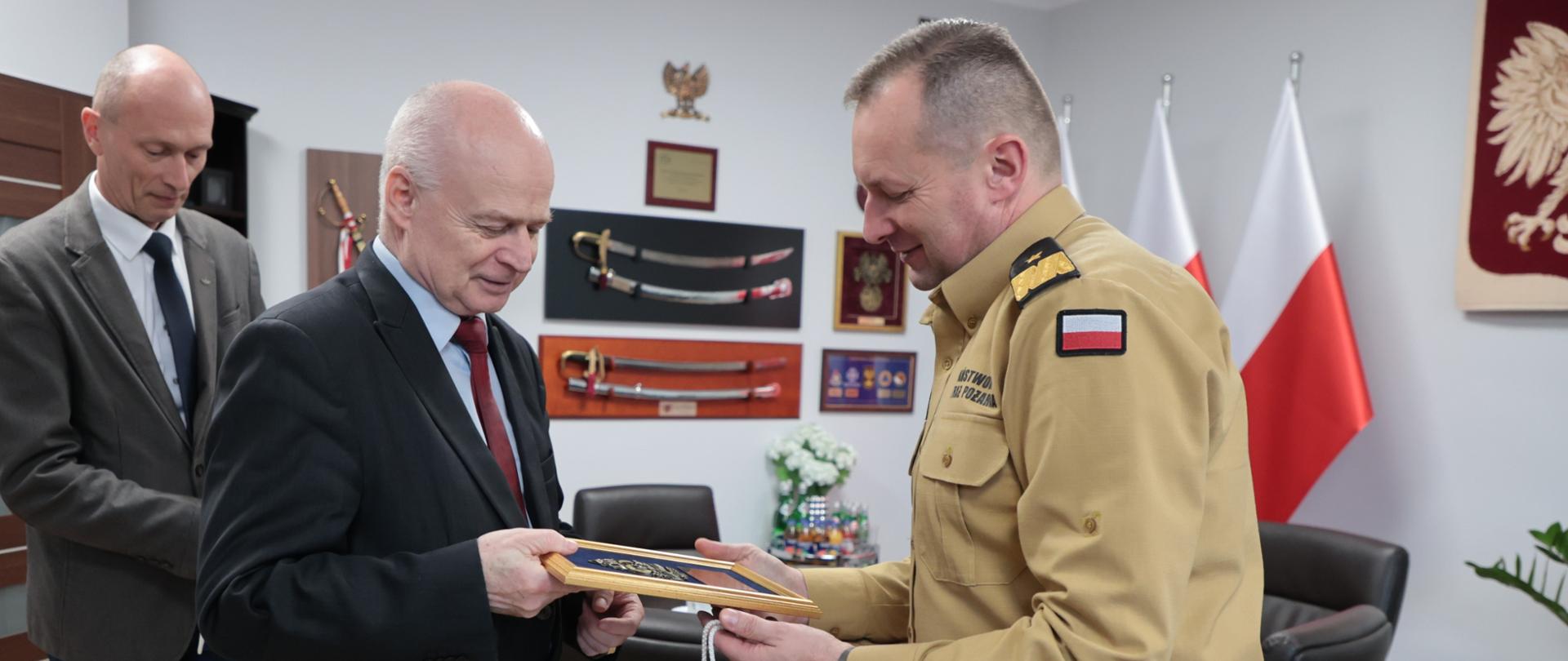 Zastępca komendanta głównego wręczający pamiątkowy ryngraf przedstawicielowi PKP Polskie Linie Kolejowe S.A