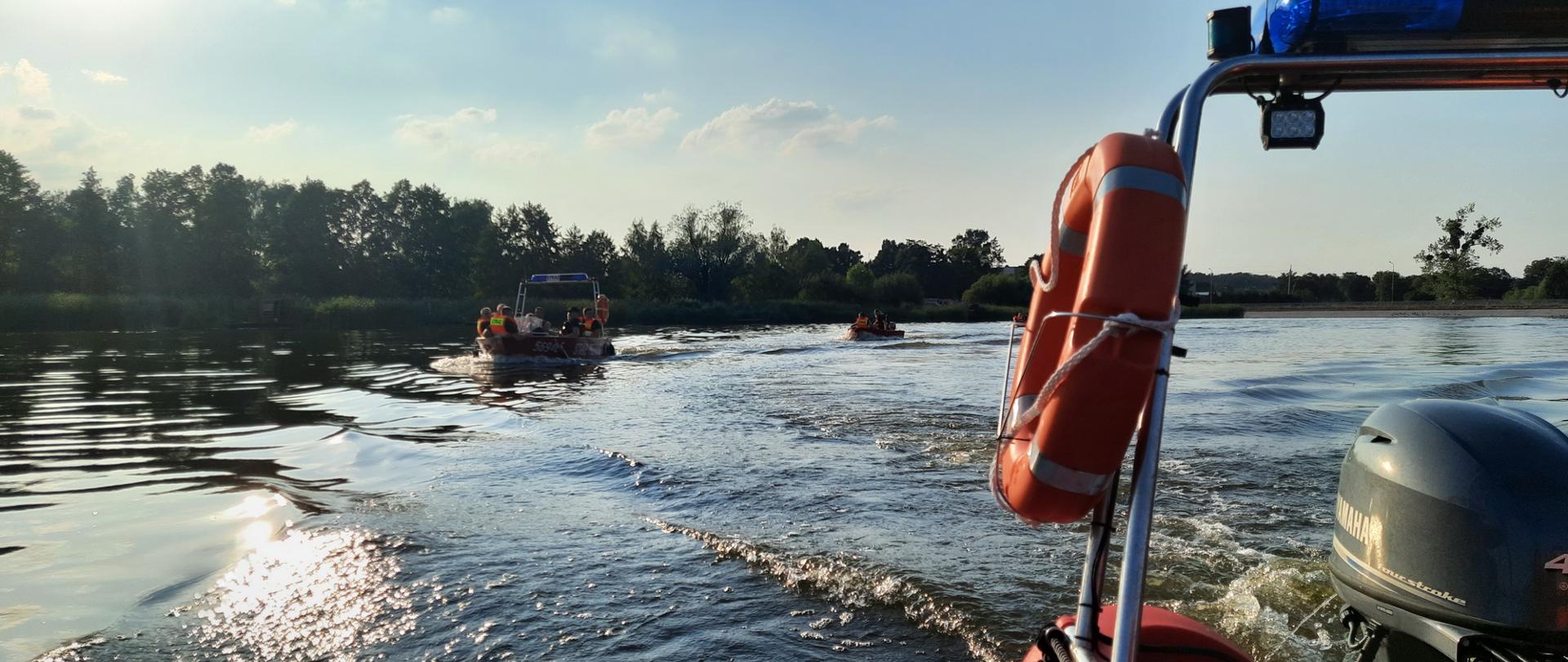 Widok z łodzi ratowniczej straży pożarnej na jezioro po którym płyną kolejne dwie łodzie ratownicze straży pożarnej
