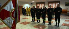 Nowo przyjęci strażacy stoją przed sztandarem wymawiając rotę ślubowania strażaka Państwowej Straży Pożarnej. W tle widać innych funkcjonariuszy KP PSP w Skarżysku-Kamiennej.
