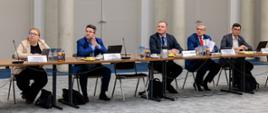 Na zdjęciu uczestnicy spotkania siedzą za stołem konferencyjnym