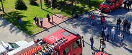 Widok z okna JRG Nr 2 w Ostrowcu na plac z wyprowadzonymi samochodami gaśniczymi. Na placu znajdują się uczestnicy OTWP