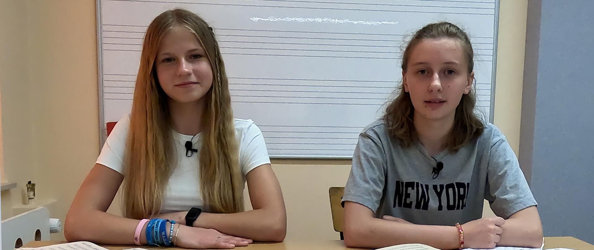 Dwie dziewczyny siedzą przed kamerą w klasie