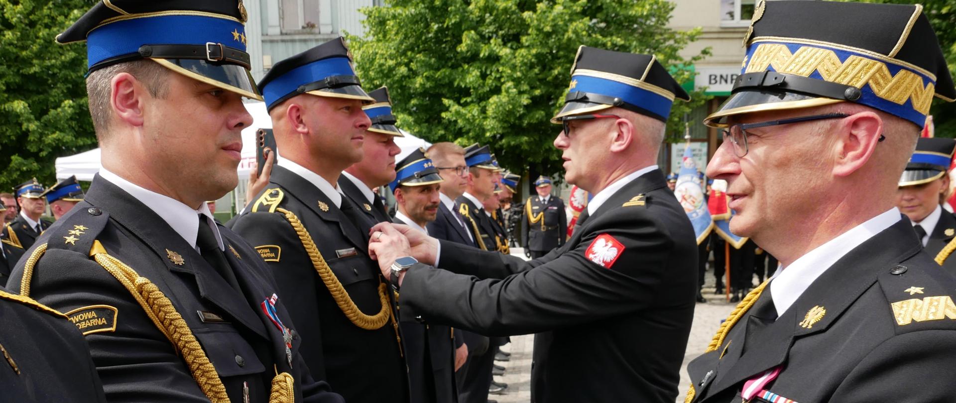 Z-ca komendanta głównego PSP wraz z komendantem wojewódzkim wręczają odznaczenie strażakowi PSP 