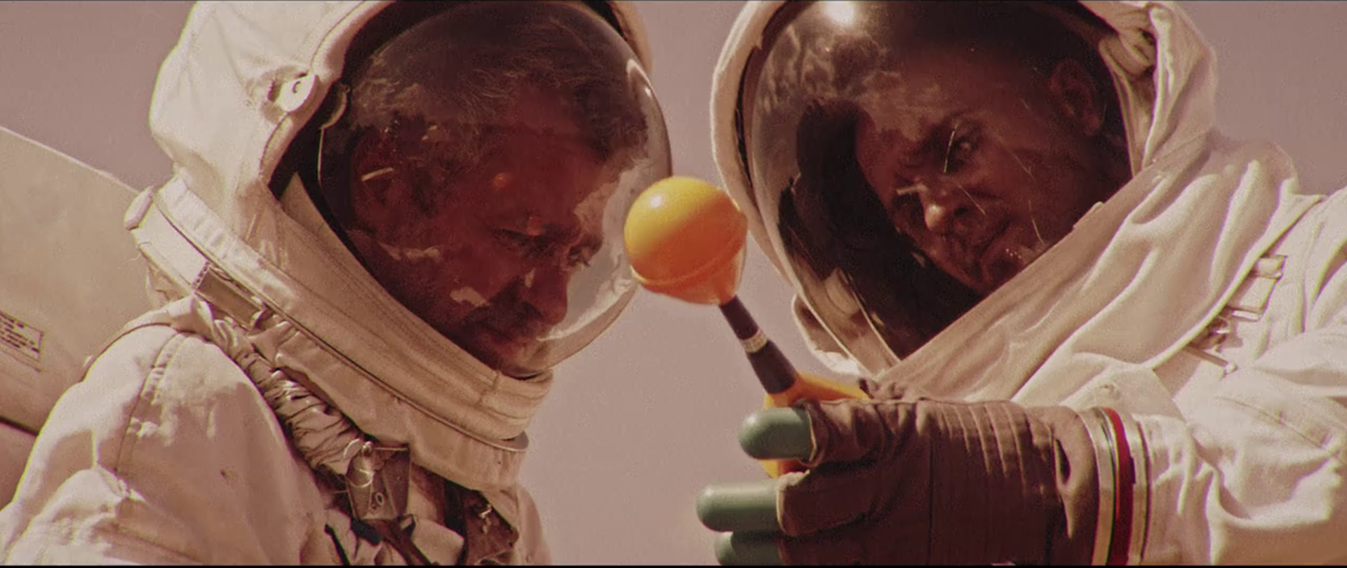 Zdjęcie przedstawiające dwóch mężczyzn w strojach kosmonautów patrzących na miernik pola elektromagnetycznego