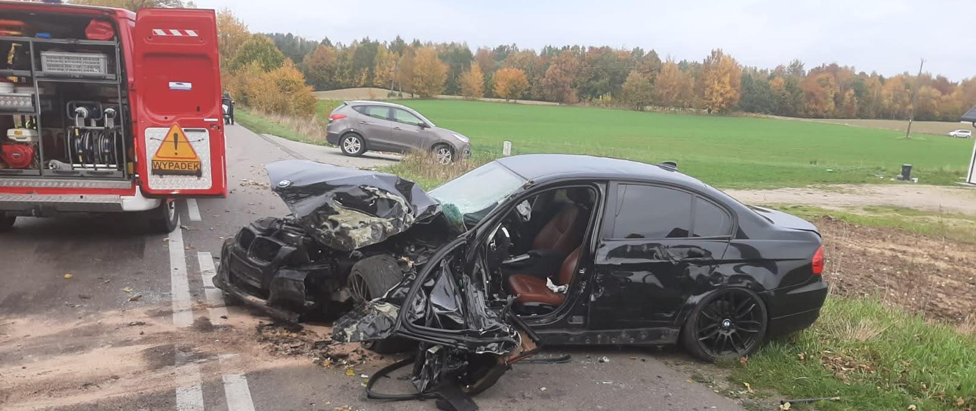 Uszkodzony samochód w wypadku, czarne BMW, widok lewego boku