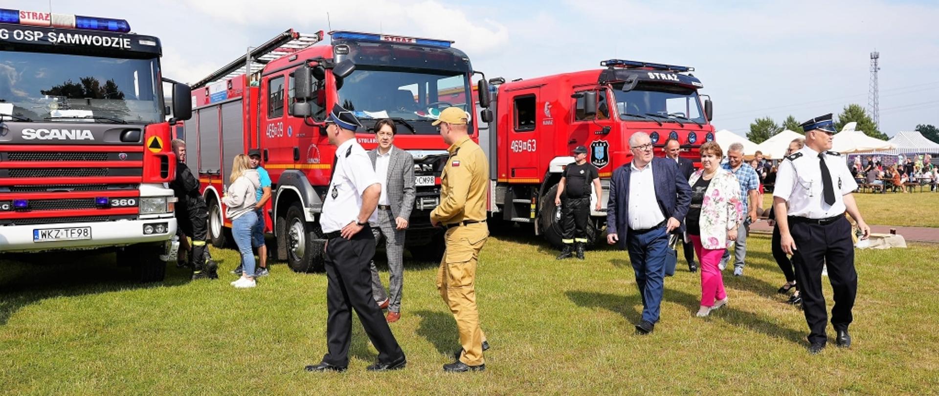 widzowie idą po boisku oglądając stojące samochody pożarnicze