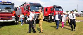 widzowie idą po boisku oglądając stojące samochody pożarnicze
