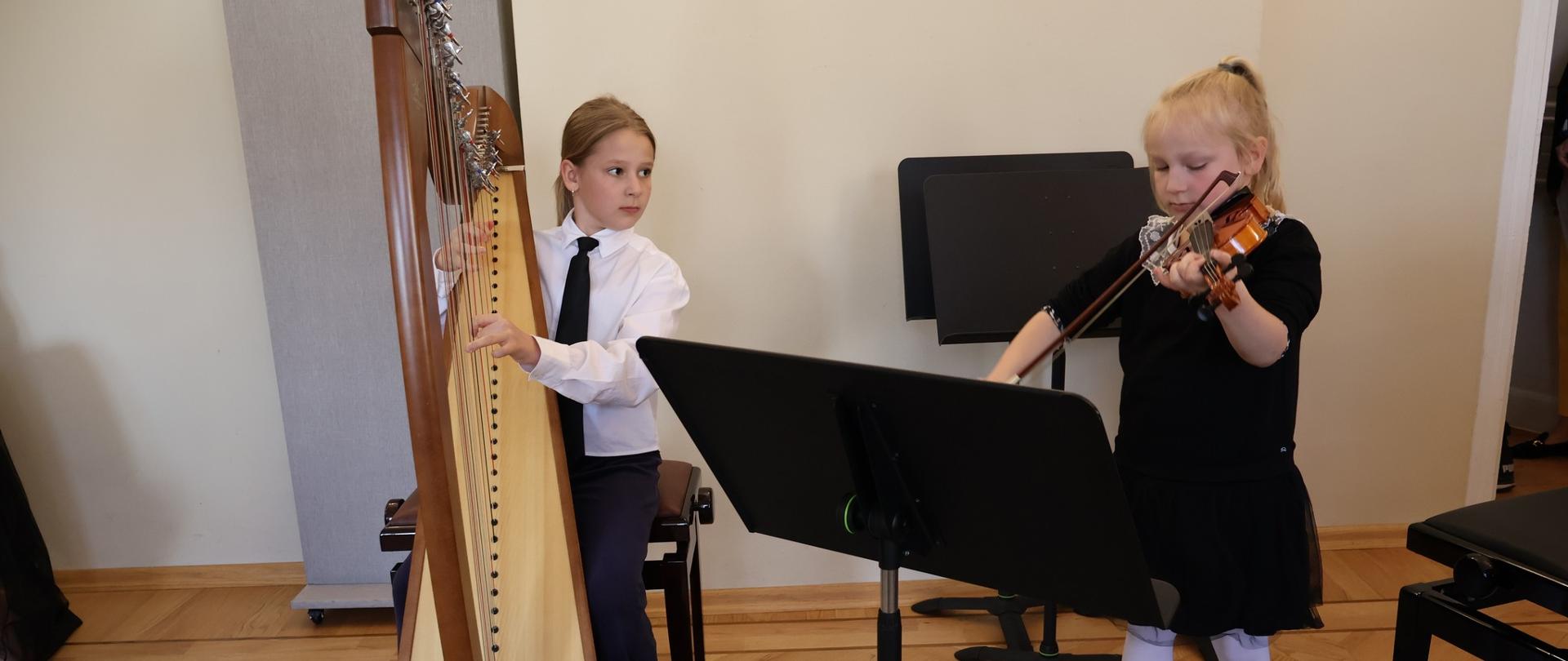 Dziewczynka grająca na harfie i młodsza grająca na skrzypcach.