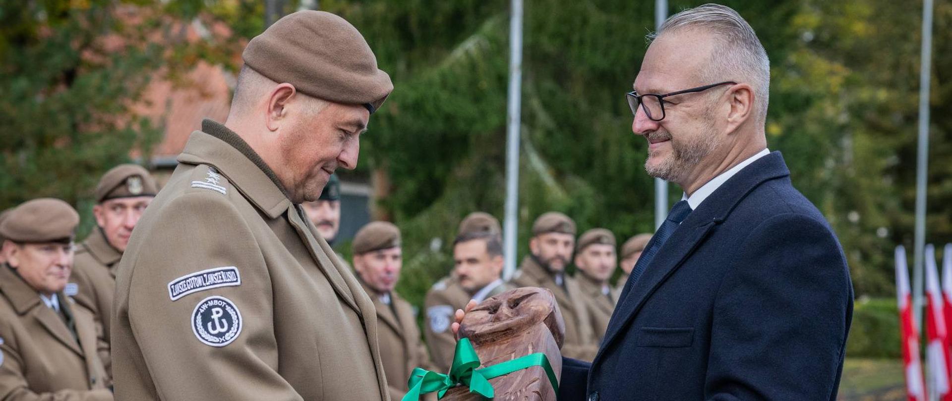 Mężczyzna przekazuje babę pruską mężczyźnie w mundurze wojskowym 