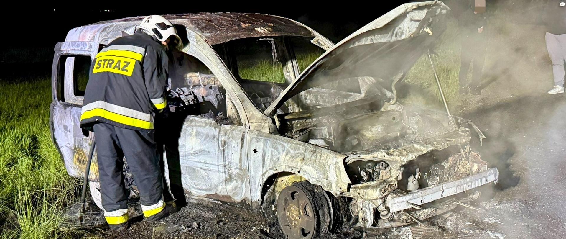 Zdjęcie przedstawia spalony samochód oraz dh OSP