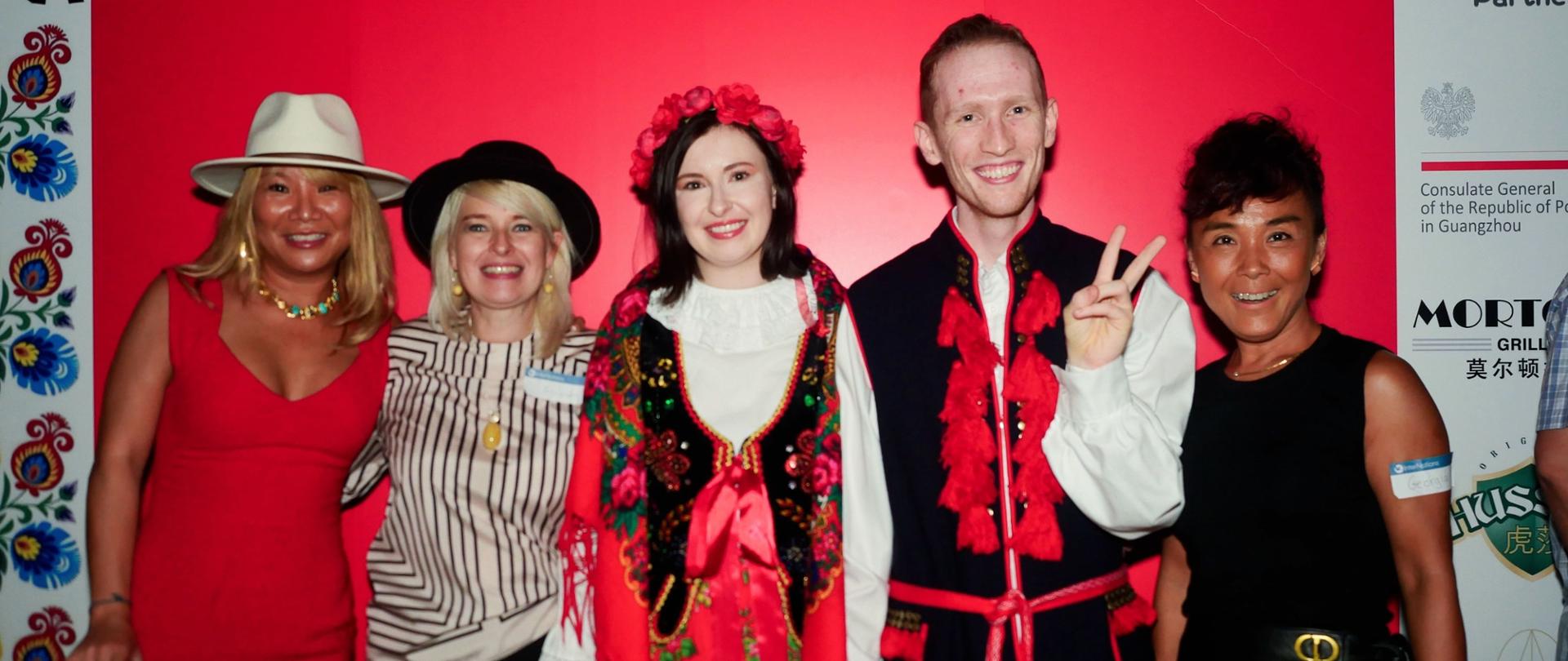 活动嘉宾在印有“A Journey to Poland – Guangzhou 2025”标志的背景板前合影，其中包括身着波兰民族服饰的参与者。