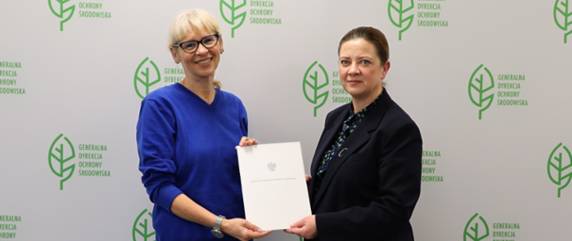 Na zdjęciu od lewej Zastępca Generalnego Dyrektora Ochrony Środowiska wręcza akt powołania Agnieszce Nowak Regionalnemu Dyrektorowi Ochrony Środowiska w Gorzowie Wielkopolskim. W tle logo liść i napis Generalna Dyrekcja Ochrony Środowiska