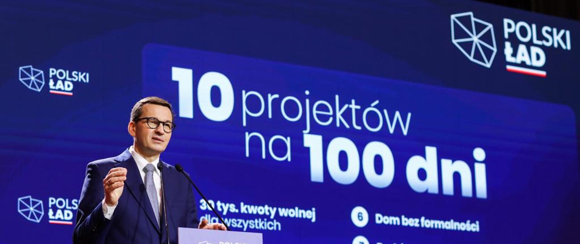 Premier na tle napisu 10 projektów na 100 dni.