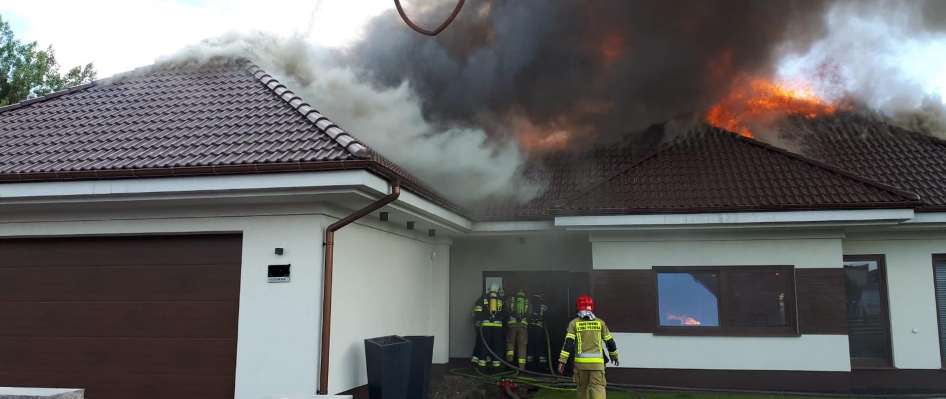 Strażacy wchodzą do palącego się domu