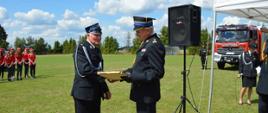 Pomorski komendant wojewódzki Państwowej Straży Pożarnej otrzymuje pamiątkowy obraz od druha ochotniczej straży pożarnej.