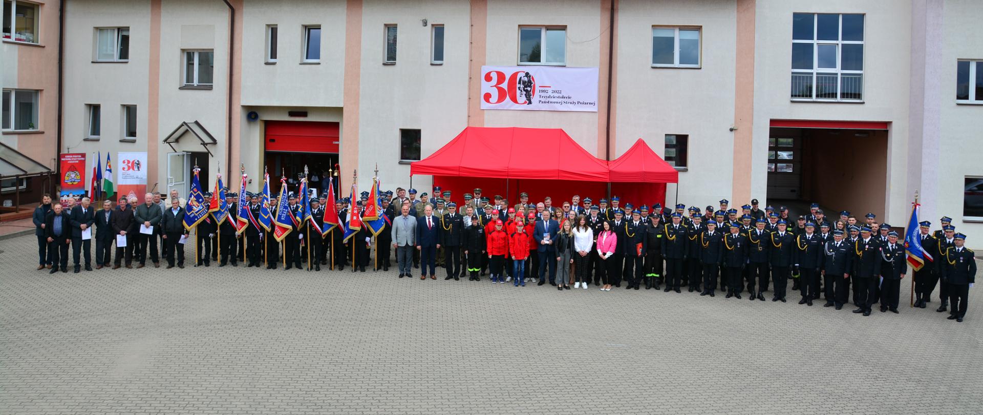 Na zdjęciu widoczni strażacy, poczty sztandarowe, przedstawiciele sejmu i senatu, służb mundurowych, władz samorządowych podczas uroczystości związanych z obchodami powiatowego Dnia Strażaka.