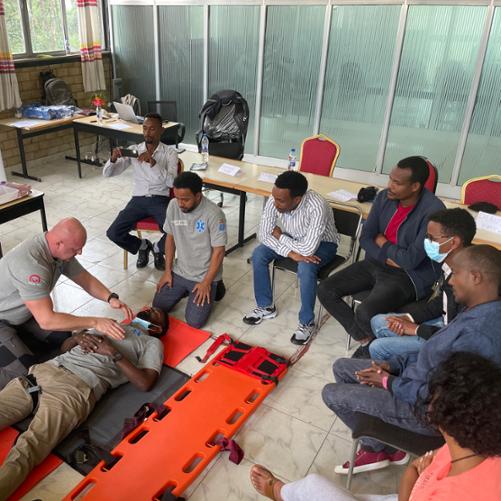 Instruktor pokazuje uczestnikom szkolenia praktyczne techniki oceny stanu poszkodowanego