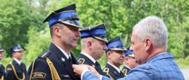 Na zdjęciu znajdują się strażacy wśród nich jeden odznaczany przez osobę cywilną