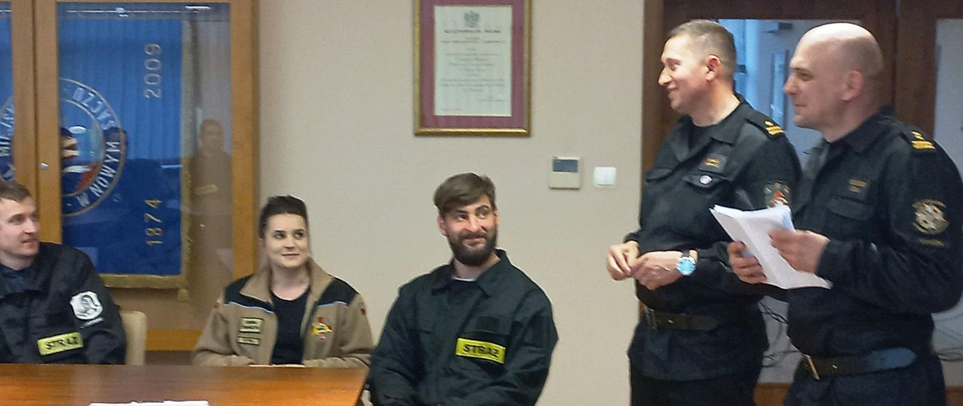 Strażacy i komisja egzaminacyjna na sali wykładowej